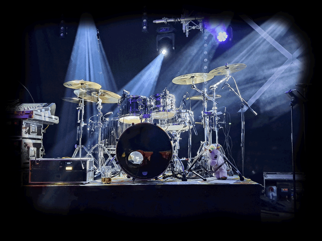Ein mikrofoniertes Schlagzeug auf einer Bühne bei welchem Live-Recording durchgeführt wird.